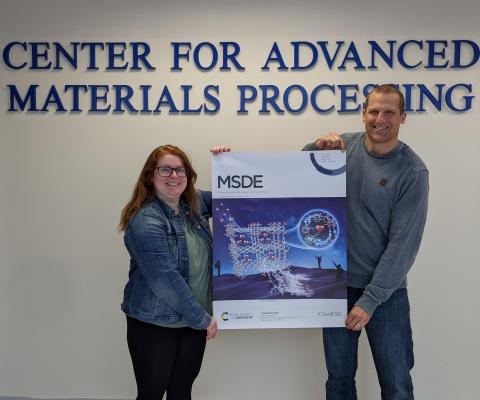 Charlene C. VanLeuven and Mario Wriedt hold an enlarged cover of MSDE Journal