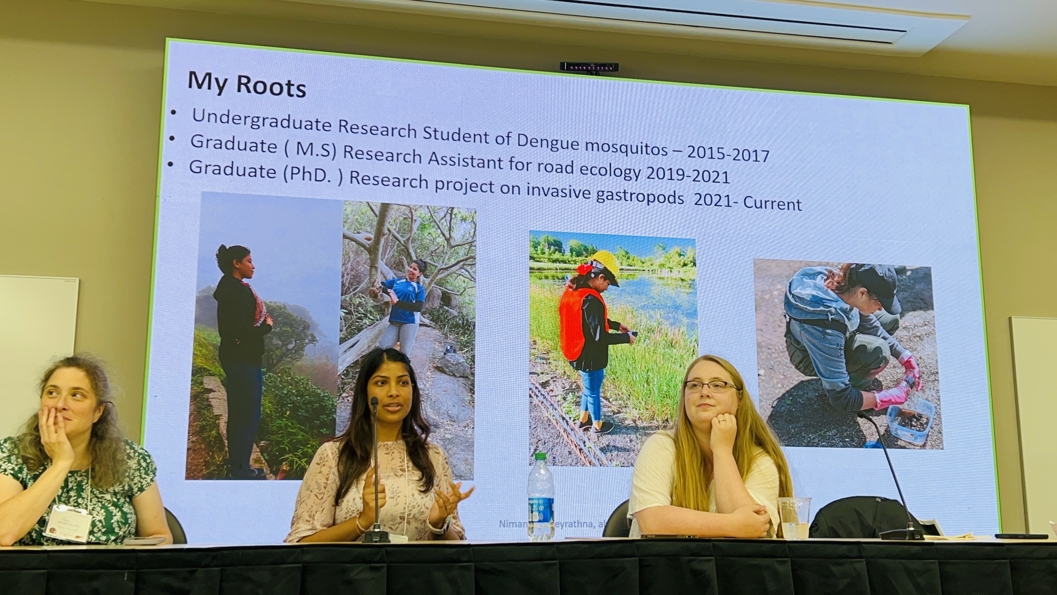 Three women sit in front of a projected slide while Nimanthi Abeyrathna speaks.