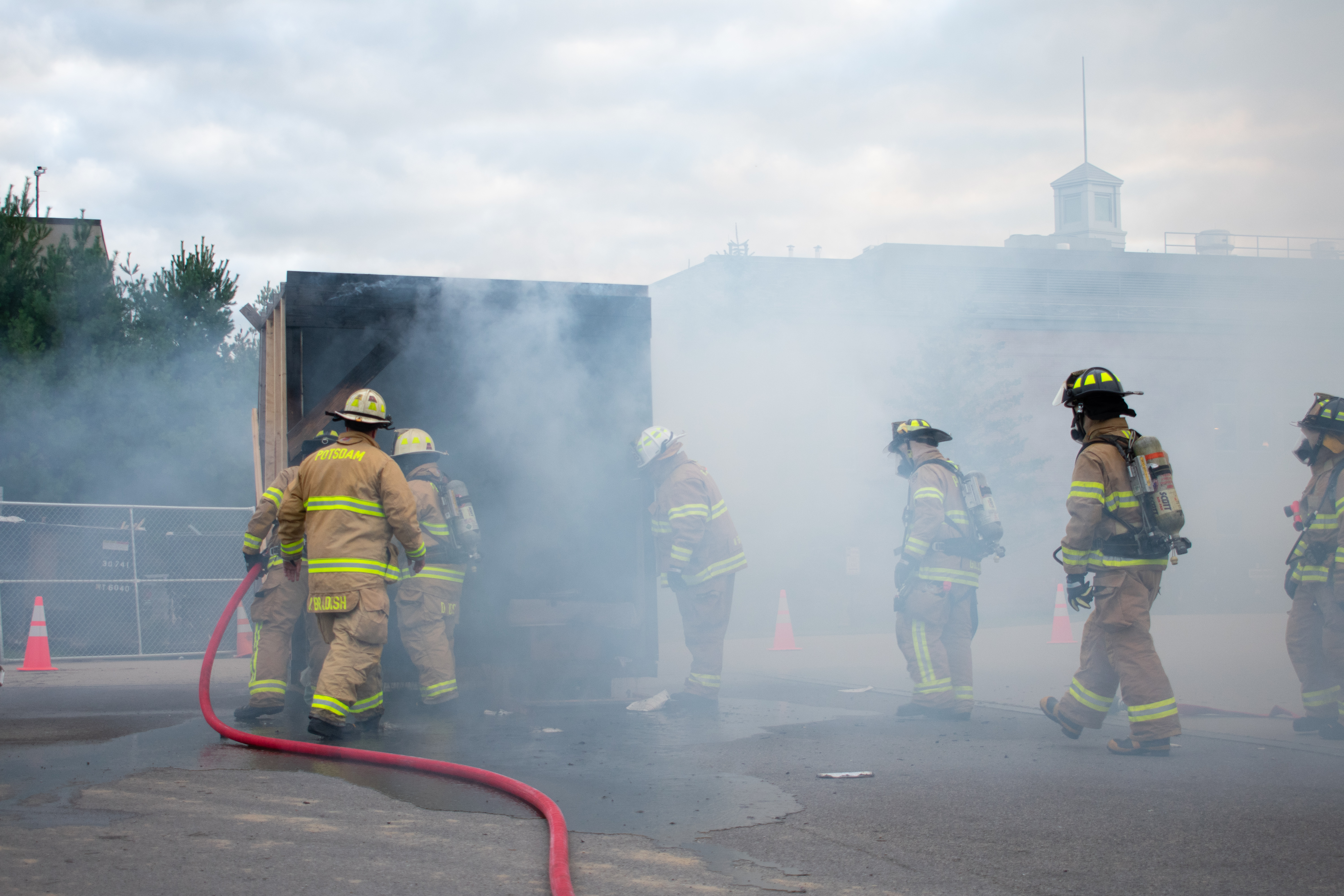 several firefighters surround a smoke-filled mock dorm room.