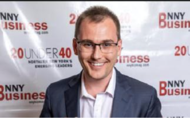 A man in a suit with glassed smiling