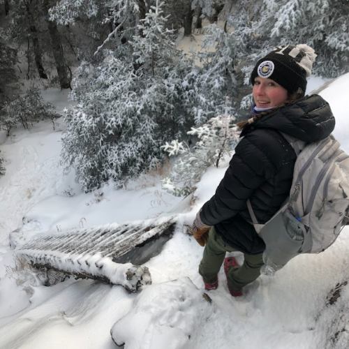 A photo of Haley May standing on top of a snowy hill.