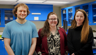 From left, one man and two women who work on Milfoil monitoring research, stand and smile for a photo inside a laboratory