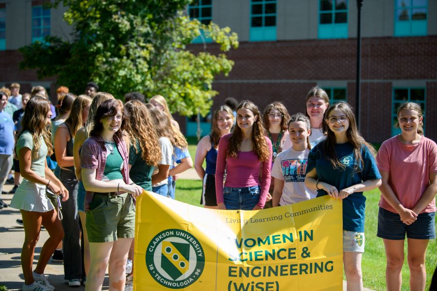 A photo of the Fall 2024 Women in Science & Engineering Living Learning community holding a banner.