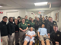 A group of EMS students poses with two EMS mannequins on stretchers