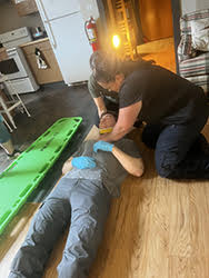 Two EMS students work on a third EMS student lying on the ground in a neck brace during an EMS course