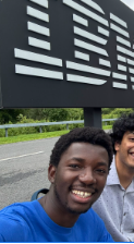 A photo of Olaouwa Ogunleye smiling in front of a IBM sign.