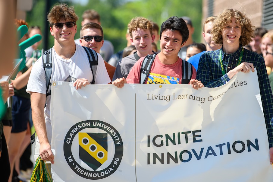  A group of students at Clarkson University walk while holding a banner reading “Ignite Innovation”.