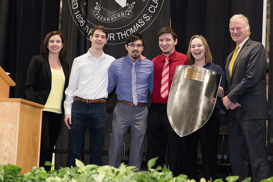 Clarkson staff and students pose for a photo during an awards ceremony on a stage