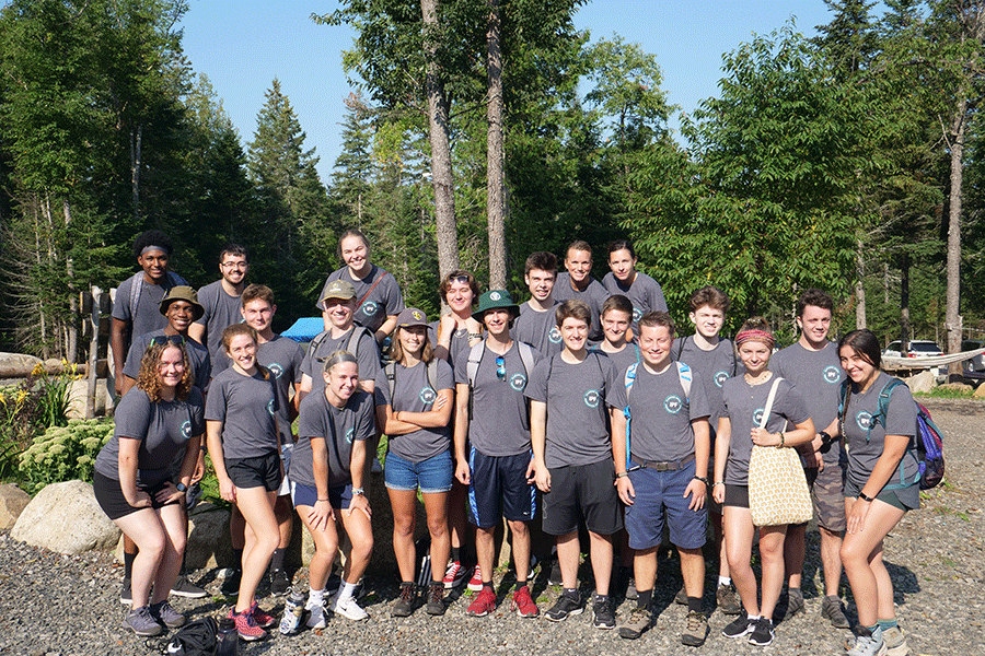 A group of Clarkson Ignite students post outside for a photo all wearing matching grey t-shirts with trees in the background
