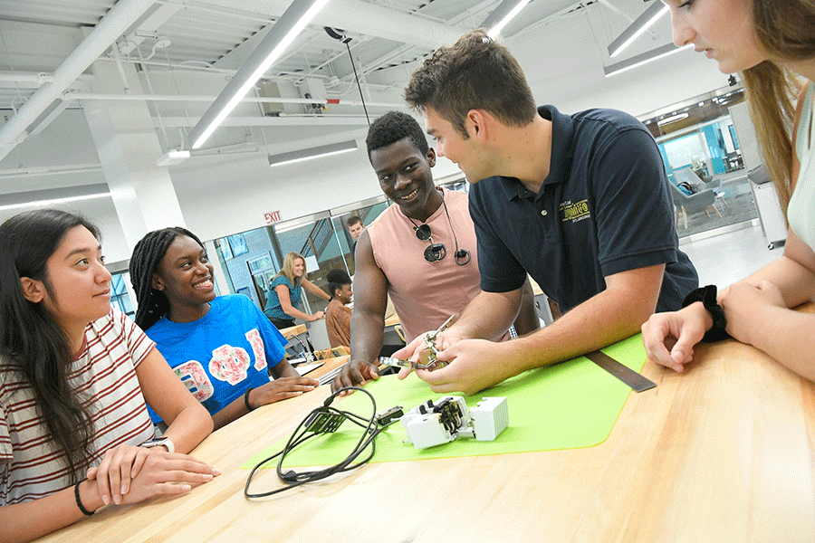 A group of Clarkson students learn how to use tools in Clarkson's Makerspace on a table