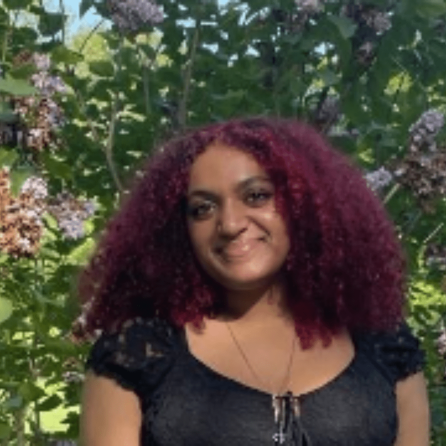 Ta'Janay Valle with tree branches and leafs behind her