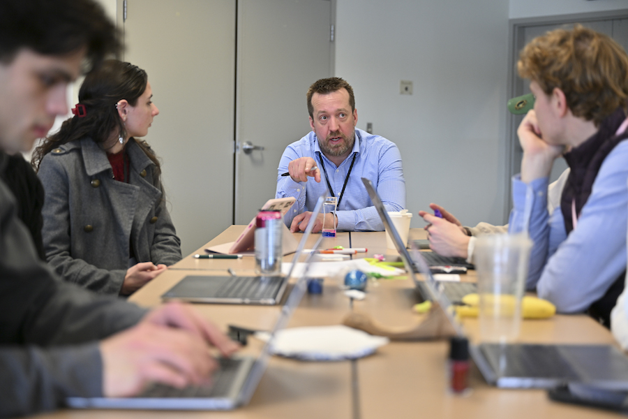 Professor talking to students at a table.