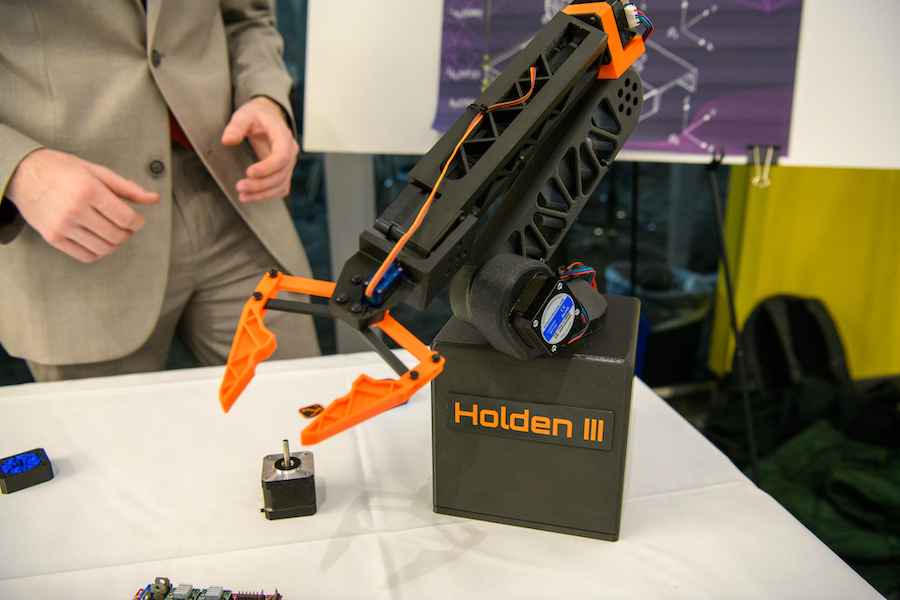 An orange and black robotic arm with the nameplate Holden III