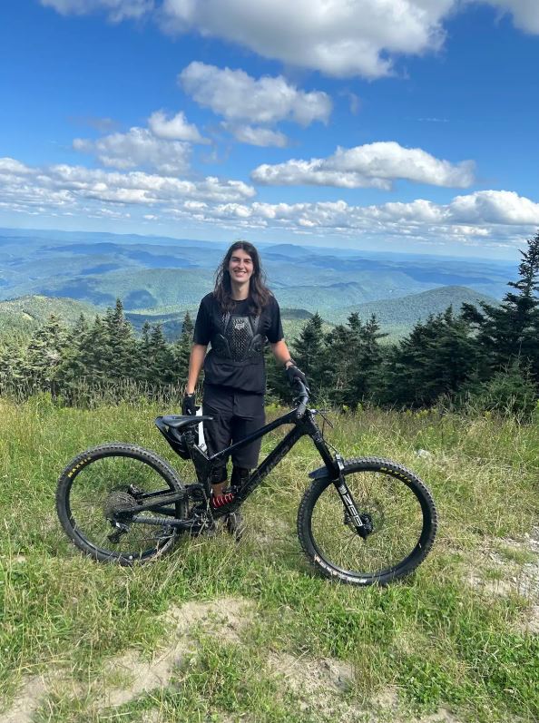 Female student on top of a hill with mountain bike.