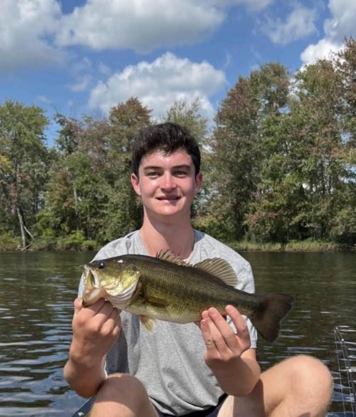 Zach Rosenthal in a boat holding a fish.