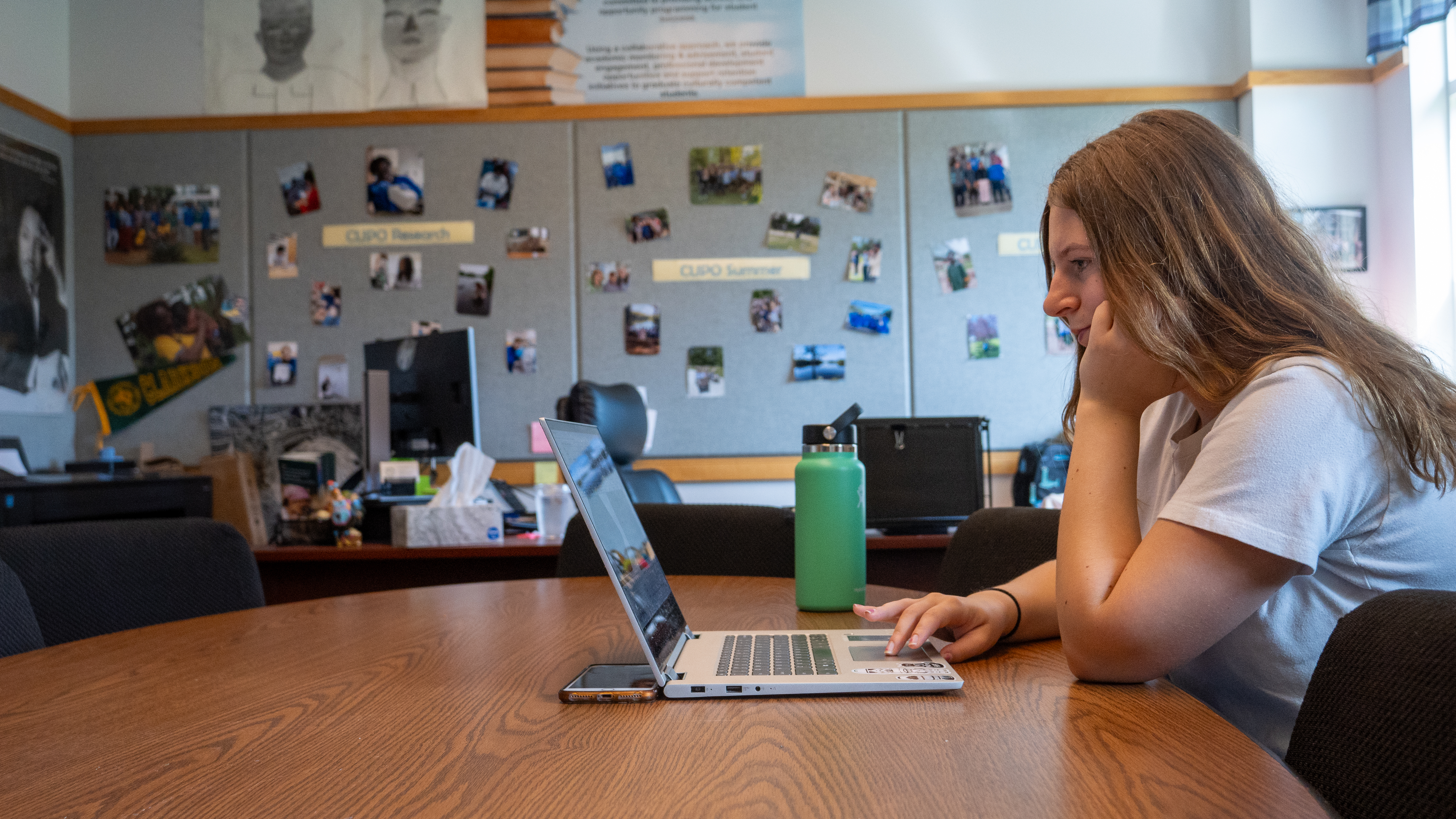 A student leans on her hand while she uses her laptop