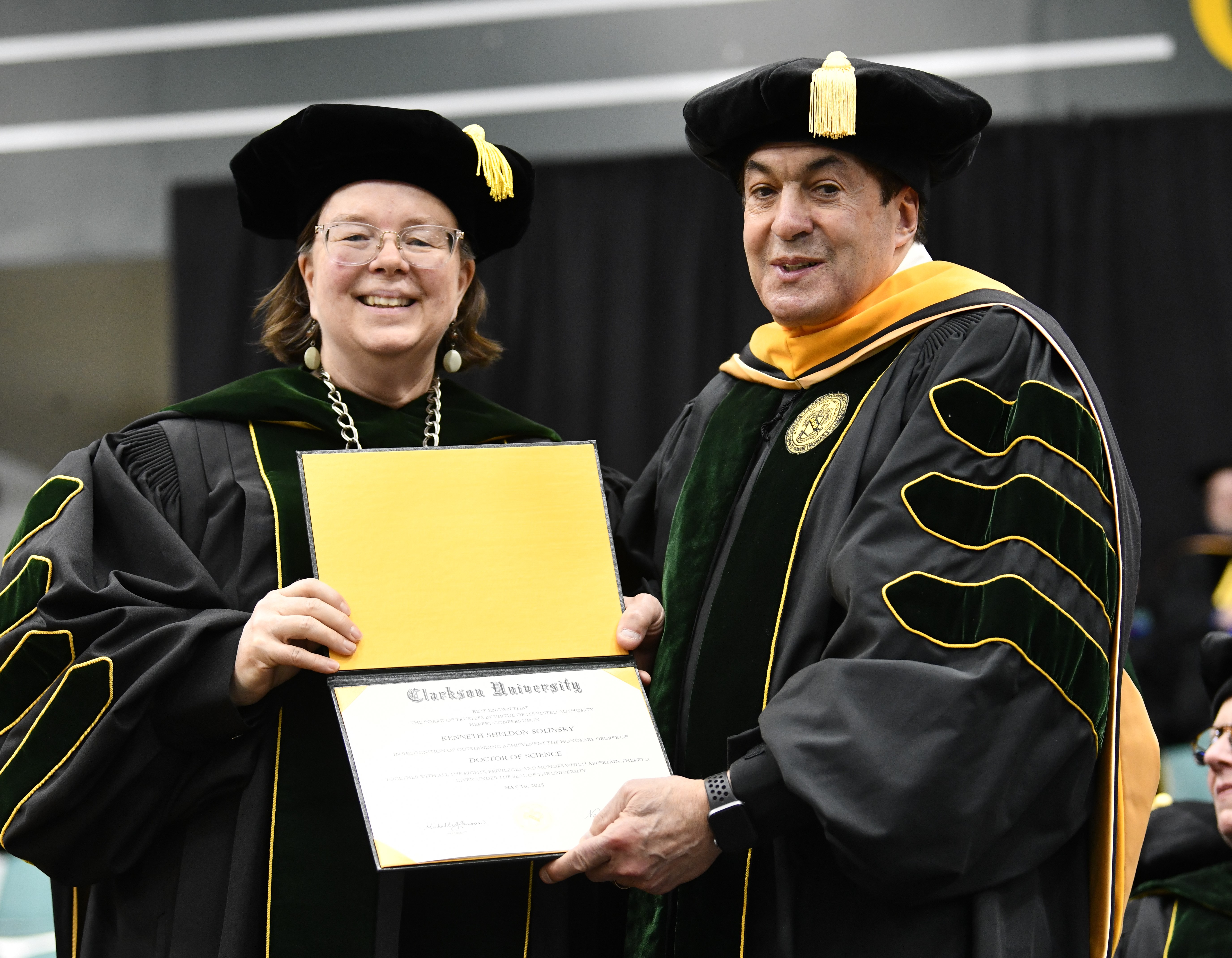 A university president presents a degree to an honorary degree recipient