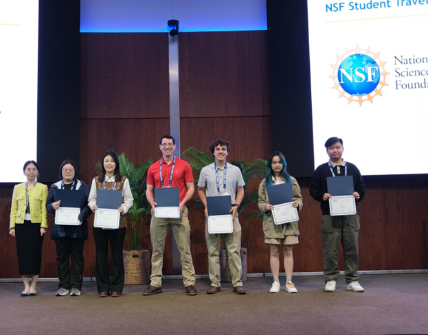 several students pose on stage holding certificates