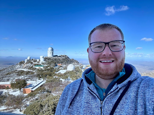 Clarkson Physics Professor Benjamin Roulston '16 poses for a photo in front of a global monument