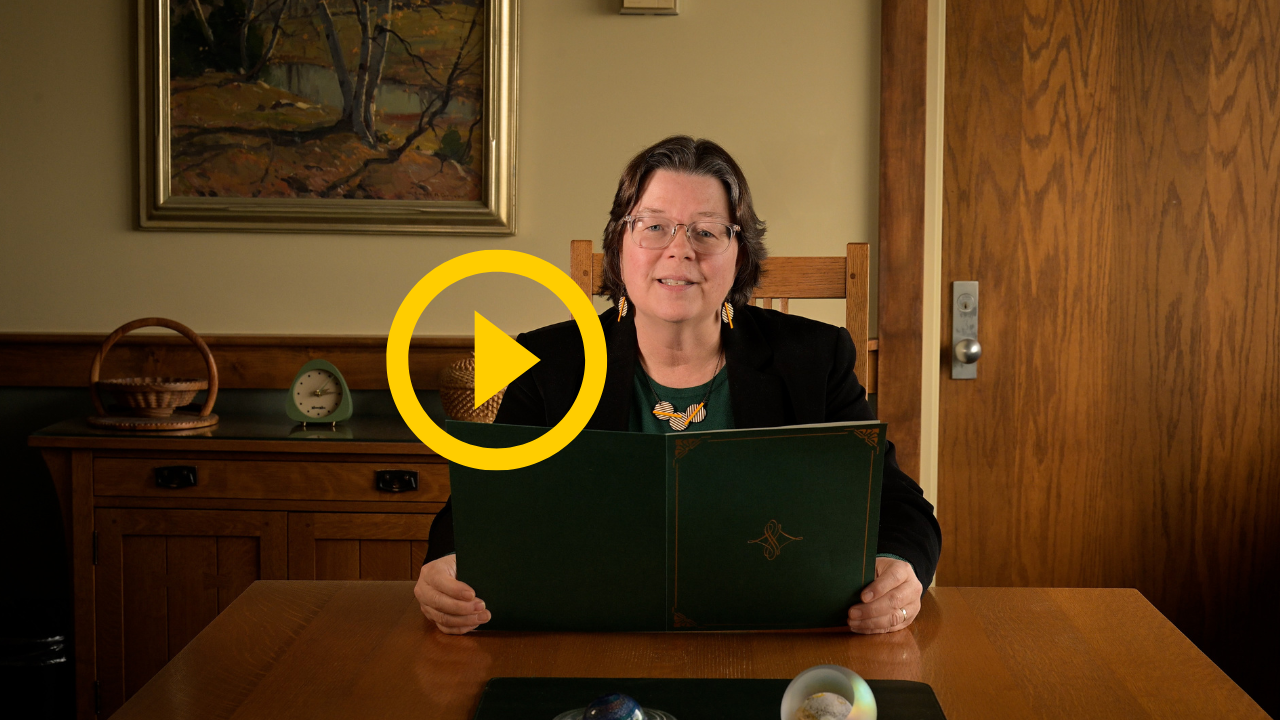 President Michelle B. Larson sits at her conference table holding her Investiture Dear Larson, for Clarkson letter