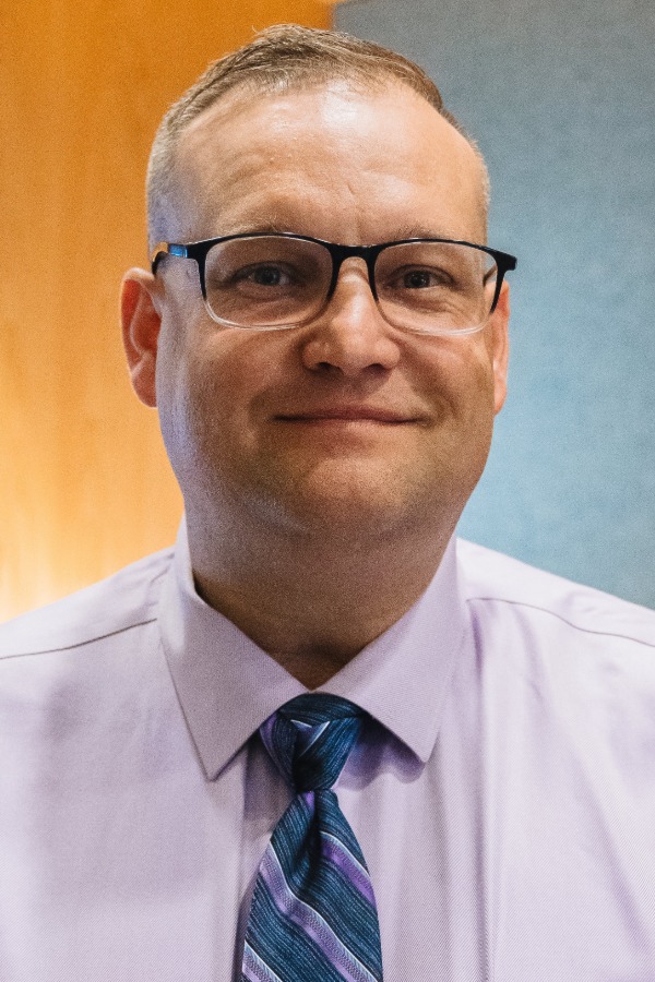 Headshot photo of Reuben Farnsworth in a dress shirt and glasses